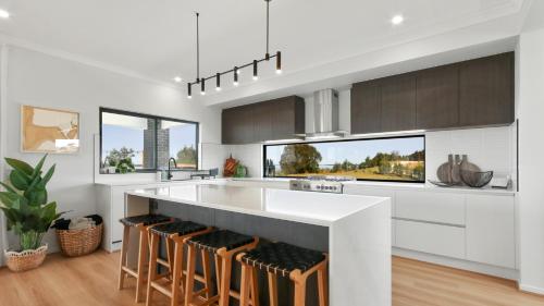 a white kitchen with a large island with bar stools at Dreamviews at Metung in Metung