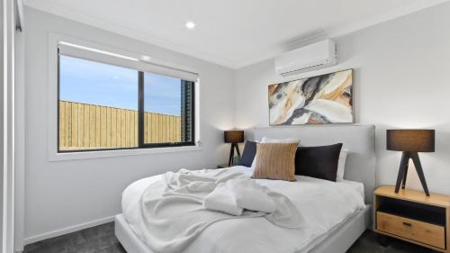 a white bedroom with a bed and a window at Dreamviews at Metung in Metung