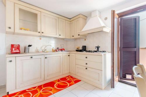 eine Küche mit weißen Schränken und einem roten Teppich in der Unterkunft La Parmigiana in Marino