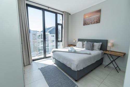 a bedroom with a bed and a large window at Modern 3 Bedroom Near The Beachfront in Summerstrand