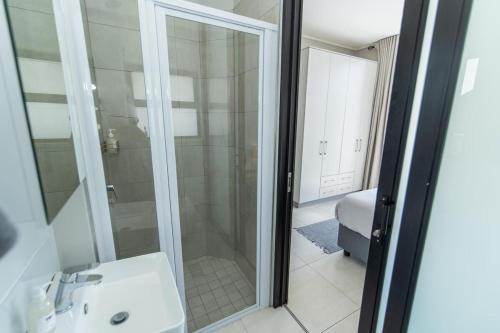 a bathroom with a glass shower and a sink at Modern 3 Bedroom Near The Beachfront in Summerstrand