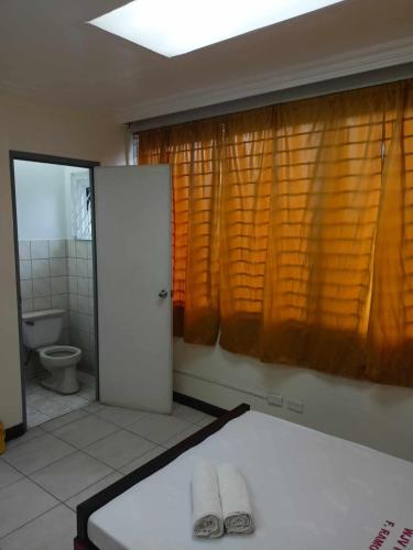 uma casa de banho com uma cama, um WC e cortinas em WJV INN RAMOS em Cebu