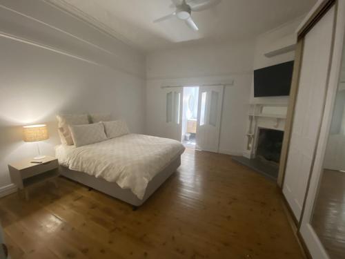 Dormitorio blanco con cama y chimenea en Perrington Estate, en Nyngan