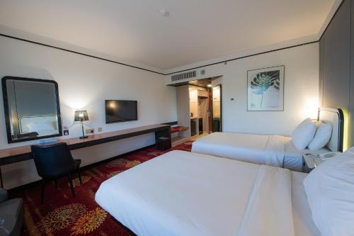 a hotel room with two beds and a television at Sabah Hotel in Sandakan