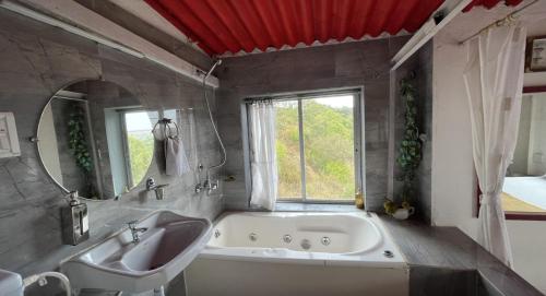 a bathroom with a tub and a sink and a mirror at Tabletop Villa Jacuzzi Suite - valley view in Panchgani