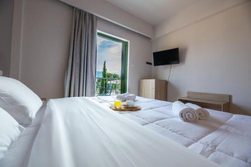 a bedroom with a large white bed with a window at Evita's Resort in Poros