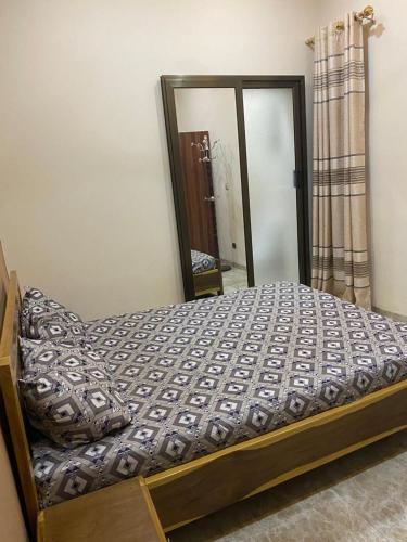 Bett in einem Schlafzimmer mit großem Spiegel in der Unterkunft Coyimo in Ouagadougou
