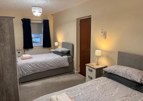 1 dormitorio con 2 camas y ventana en 3 Bedroom Apartment, Ballymena, The Wee Stop Gap, en Ballymena