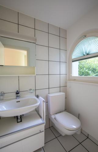 a white bathroom with a toilet and a sink at Villa Incanto in Ascona