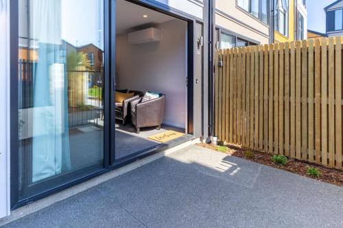 a sliding glass door with a couch inside of a house at Vibrant Inner City Escape Near New Regent Street in Christchurch