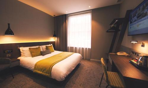 a bedroom with a bed and a desk and a window at Best Western Plus Delmere Hotel in London