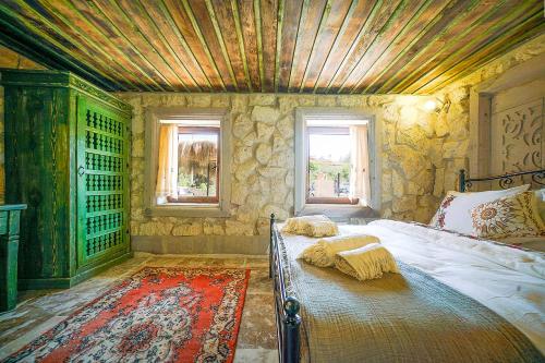 a bedroom with a bed with a wooden ceiling and windows at Aysel Inn House in Goreme