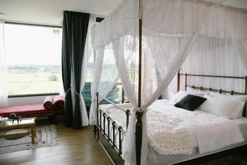 a bedroom with a canopy bed and a large window at Pupah Kanna Pua-ปู๋ ป๋าล์ คันนา ปัว in Pua