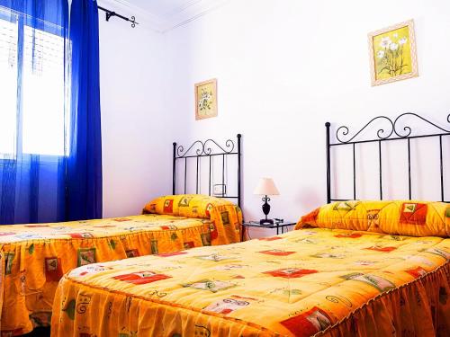 two beds in a room with yellow sheets at Apartamento en Conil de la Frontera in Conil de la Frontera