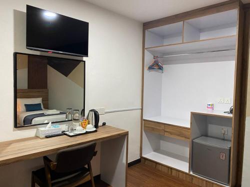 a bedroom with a bed and a desk with a television at Assalam Hotel in Kota Bharu