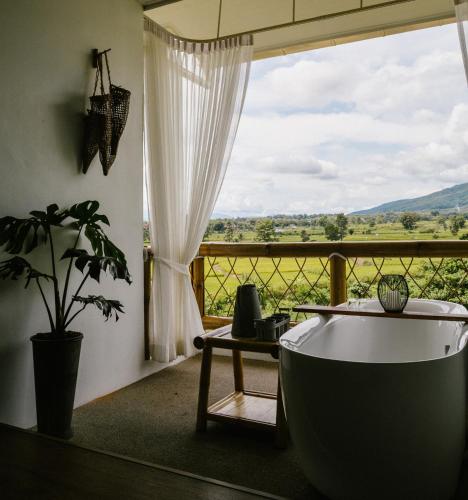 a bath tub sitting in a room with a window at Pupah Kanna Pua-ปู๋ ป๋าล์ คันนา ปัว in Pua
