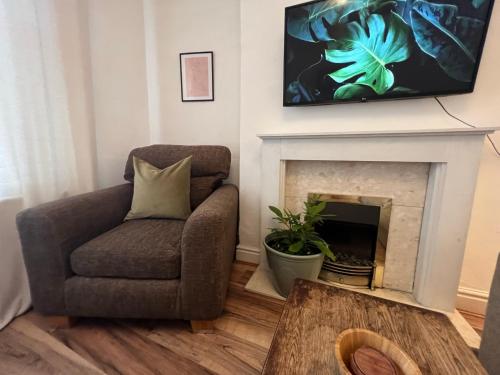 a living room with a chair and a tv over a fireplace at Liverpool Ivy House - 4 Bedrooms in Liverpool