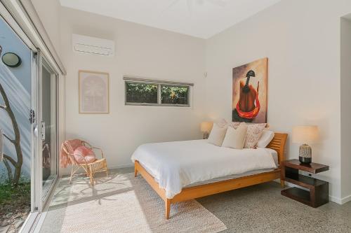 a bedroom with a bed and a painting on the wall at Zen Garden Beach House Casuarina by uHoliday in Casuarina