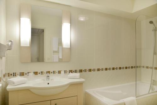 a bathroom with a sink and a tub and a mirror at Adonis Divonne-Les-Bains Résidence Du Lac in Divonne-les-Bains
