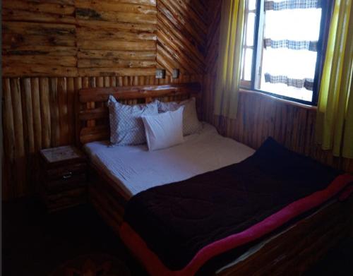 1 dormitorio con 1 cama en una cabaña de madera en Kapchakays Farmstay by StayApart, en Kalimpong
