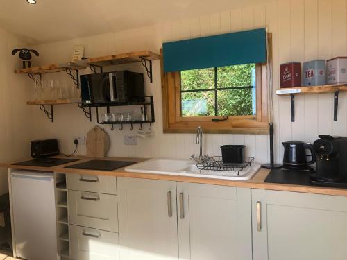 cocina con armarios blancos, fregadero y ventana en No 1 Hut Lane, a cosy Hut, heating, hot water and a magnificent view for 2, en Dorchester