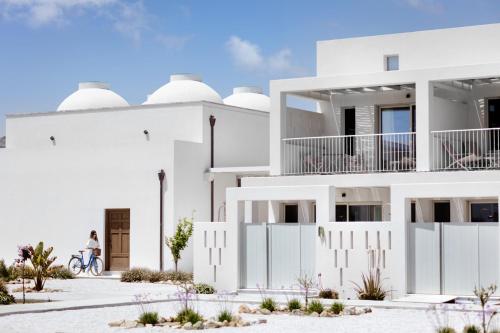 uma mulher a andar de bicicleta em frente a um edifício branco em ALERÓ Seaside Skyros Resort em Skiros