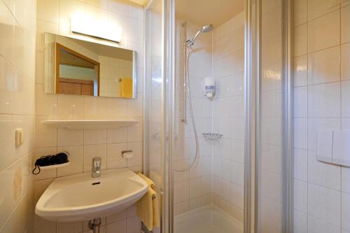 a white bathroom with a sink and a shower at Berggasthof Bärnstatt in Scheffau am Wilden Kaiser