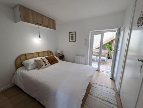 ein Schlafzimmer mit einem weißen Bett und einer Glasschiebetür in der Unterkunft Le Studio Jungle in Digoin