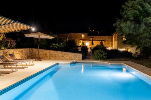 a swimming pool at night with a table and an umbrella at Grano - Casa Bella Vista in Force