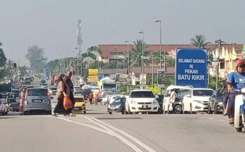 a group of people crossing a busy street with cars at Roomstay "Ghumah Uwan" in Batu Kikir