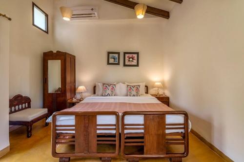 a bedroom with a bed and a table and a chair at SaffronStays Elderflower in Alibaug