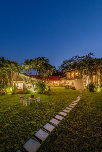 a garden with a pathway in front of a house at SaffronStays Elderflower in Alibaug