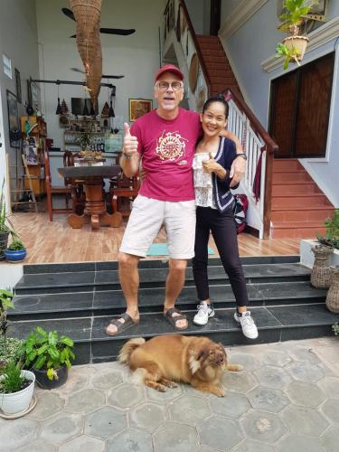 a man and a woman standing on steps with a dog at Bloom Garden Bed & Breakfast in Siem Reap