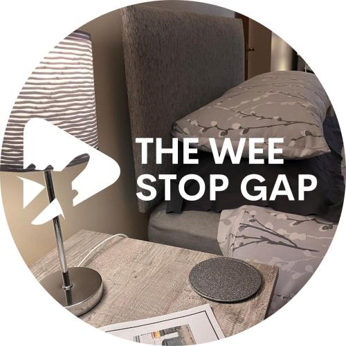 a table with a bed and a sign that reads the we stop gap at 3 Bedroom Apartment, Ballymena, The Wee Stop Gap in Ballymena