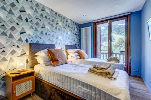 deux lits dans une chambre aux murs bleus dans l'établissement Sabaudia Appartement deux chambres plein sud et à proximité du centre du village, à Morzine