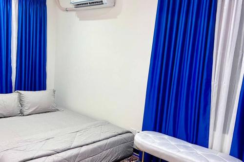 a small bedroom with blue curtains and a bed at Villa Rolling Hills Depan Trans Mall Makassar in Makassar
