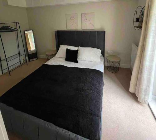 a bedroom with a large black bed with two pillows at Gatwick Airport Apartment in Crawley