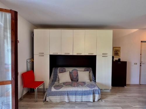 a bedroom with a bed with white cabinets and a red chair at il lauro apartment in Lazise