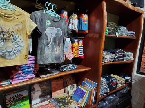 a book shelf filled with shirts and other merchandise at Twyfelfontein Country Lodge in Twyfelfontein
