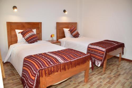 two beds in a hotel room with two beds at Hotel Inka Pisac in Pisac