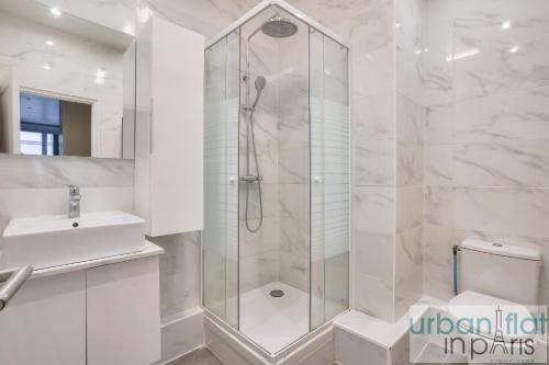 une salle de bain blanche avec une douche et un lavabo dans l'établissement 23 - Charming 3BDR Parisian Apartment in Montorgueil, à Paris