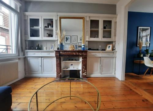 a kitchen with white cabinets and a glass table at Charmante maison 3 chambres avec cour in Lille