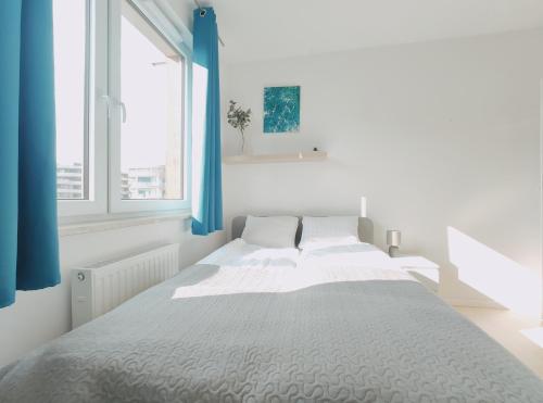 a white bedroom with a large bed with blue curtains at Dobrego Pasterza 120D by Homeprime in Kraków