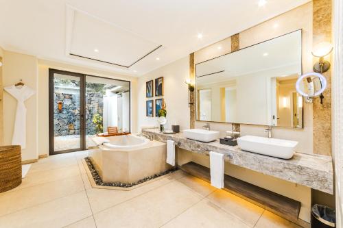 a bathroom with two sinks and a large mirror at Maradiva Villas Resort and Spa in Flic-en-Flac