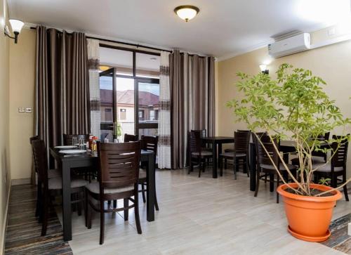 a dining room with a table and chairs and a plant at Legacy Suites in Lilongwe