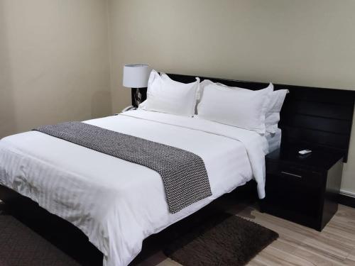 a bedroom with a large bed with white sheets and pillows at Legacy Suites in Lilongwe