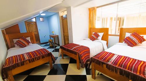 a room with three beds and a checkered floor at Hotel Inka Pisac in Pisac