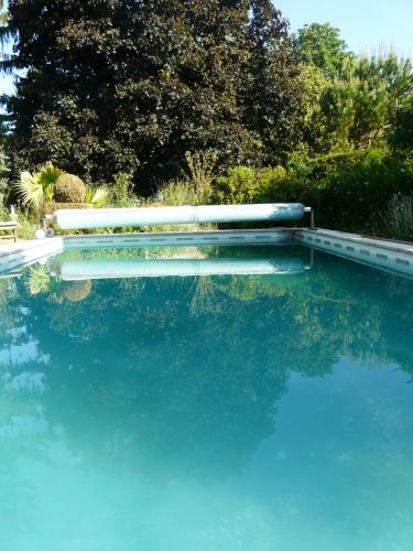 uma piscina de água azul com árvores ao fundo em La Closeraie Saint-Girons Le Gîte em Saint-Girons-dʼAiguevives