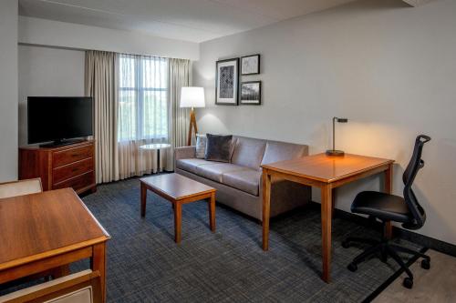 a hotel room with a couch and a desk and a television at Residence Inn by Marriott Chesapeake Greenbrier in Chesapeake