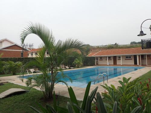 uma piscina com uma palmeira em frente a uma casa em Khael Glory home offers 247 security em Kampala